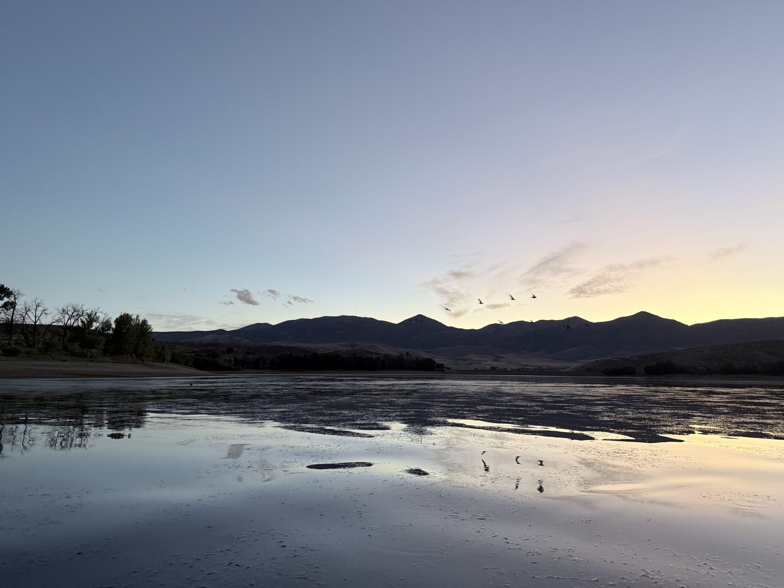 Sunset over mountain lake with birds in flight